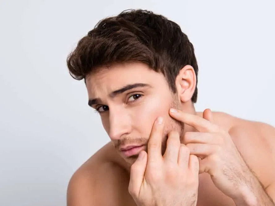 Stock photograph of a model: a young man with bare shoulders touches his cheek and looks into the distance