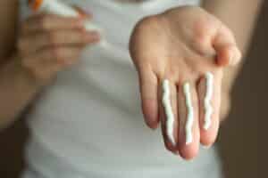 Woman holding out her hand with multiple sunscreen options on her fingers, unsure which is best for acne